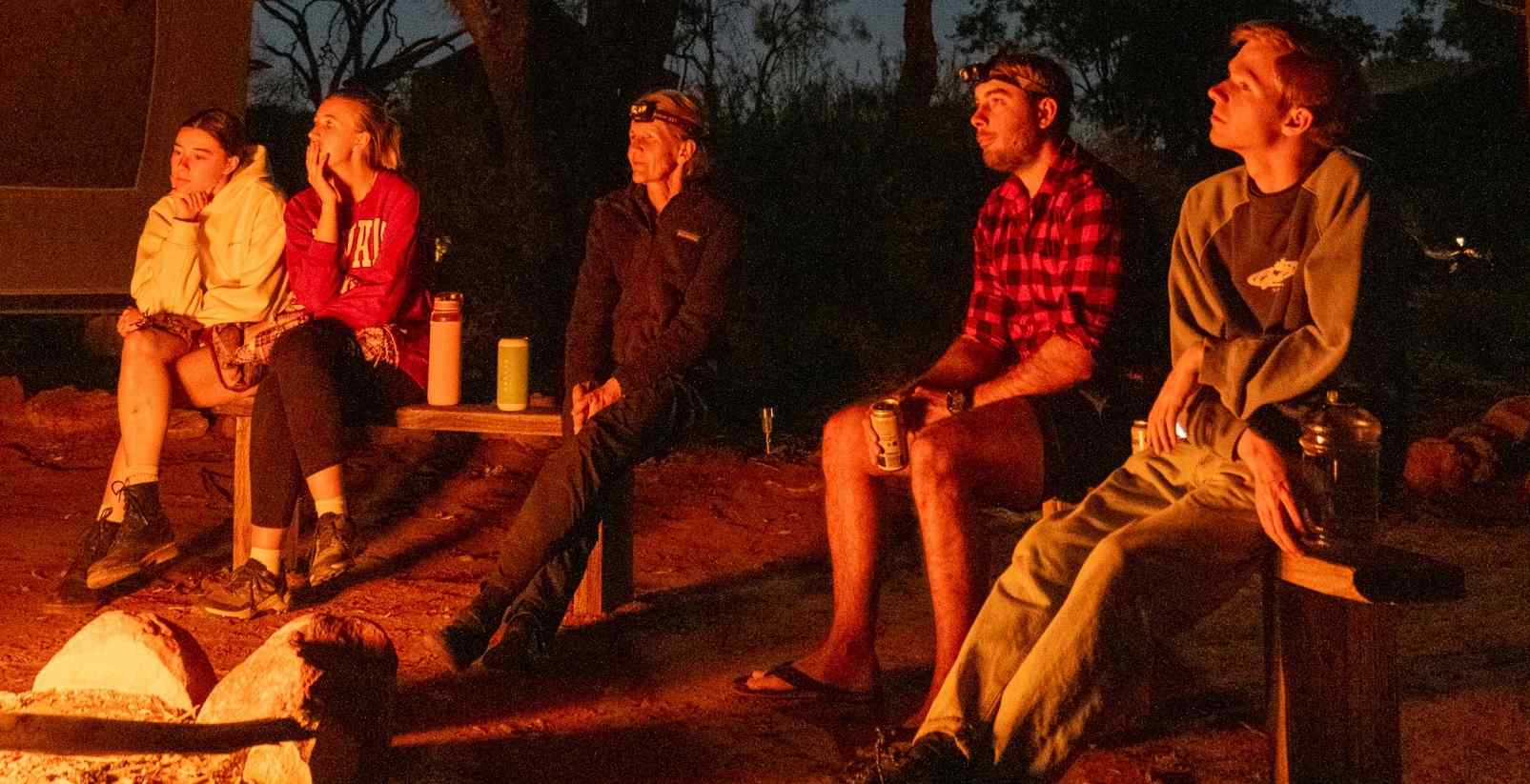 people sitting around campfire at night