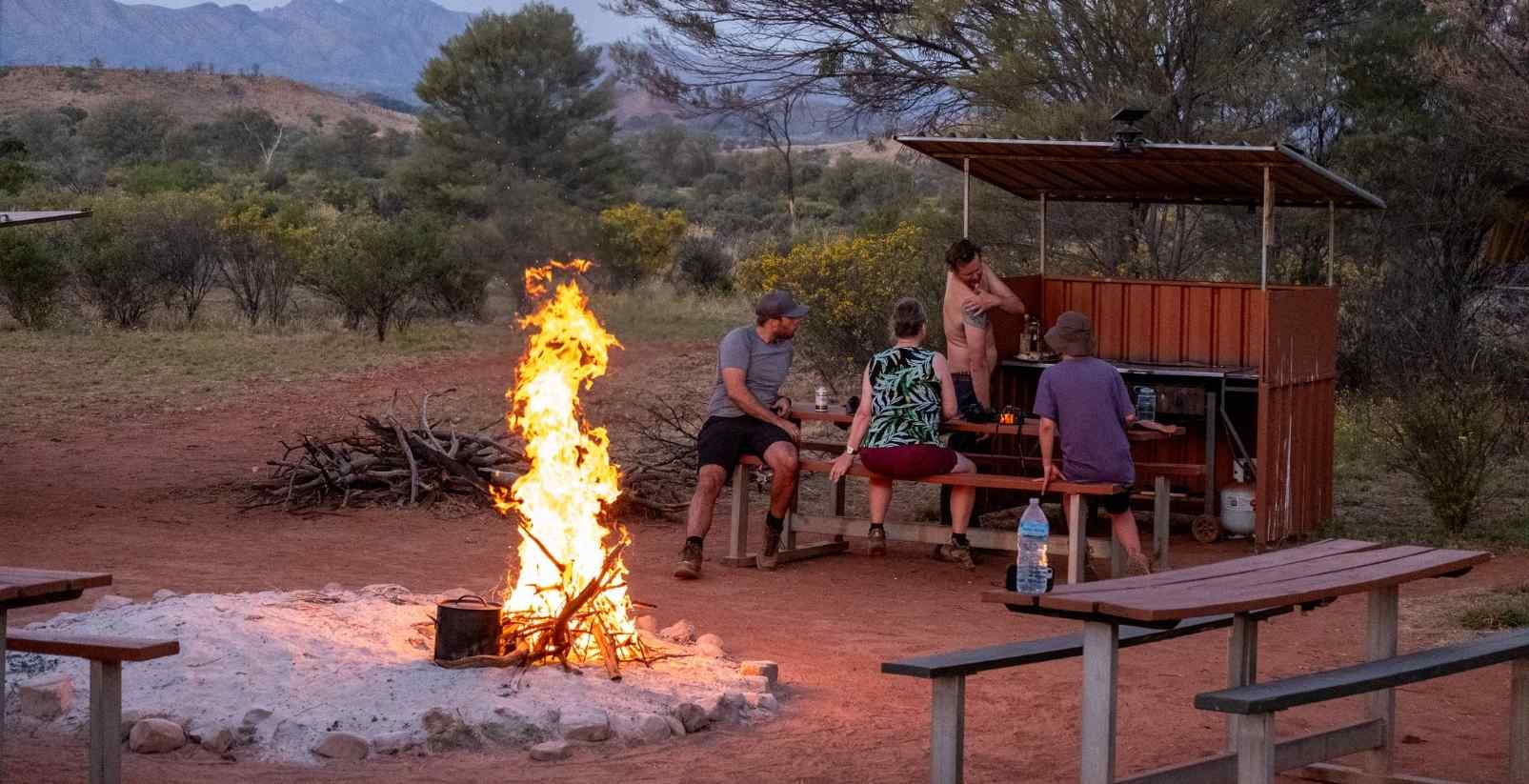 people sitting around campfire near uluru