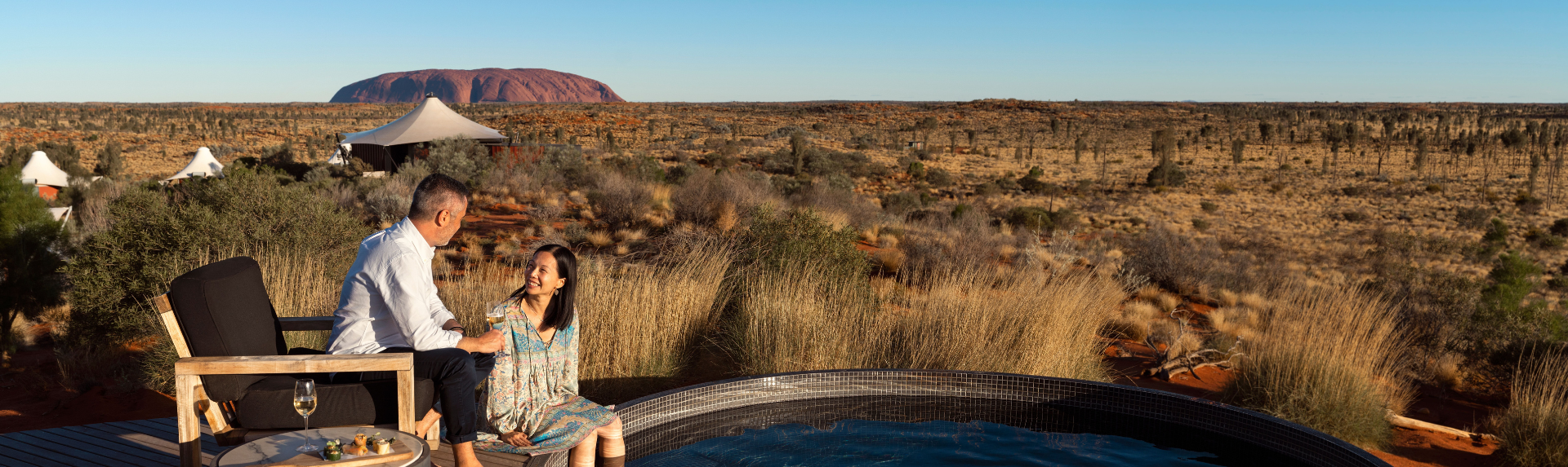 Couple sitting by edge of plunge pool near Uluru