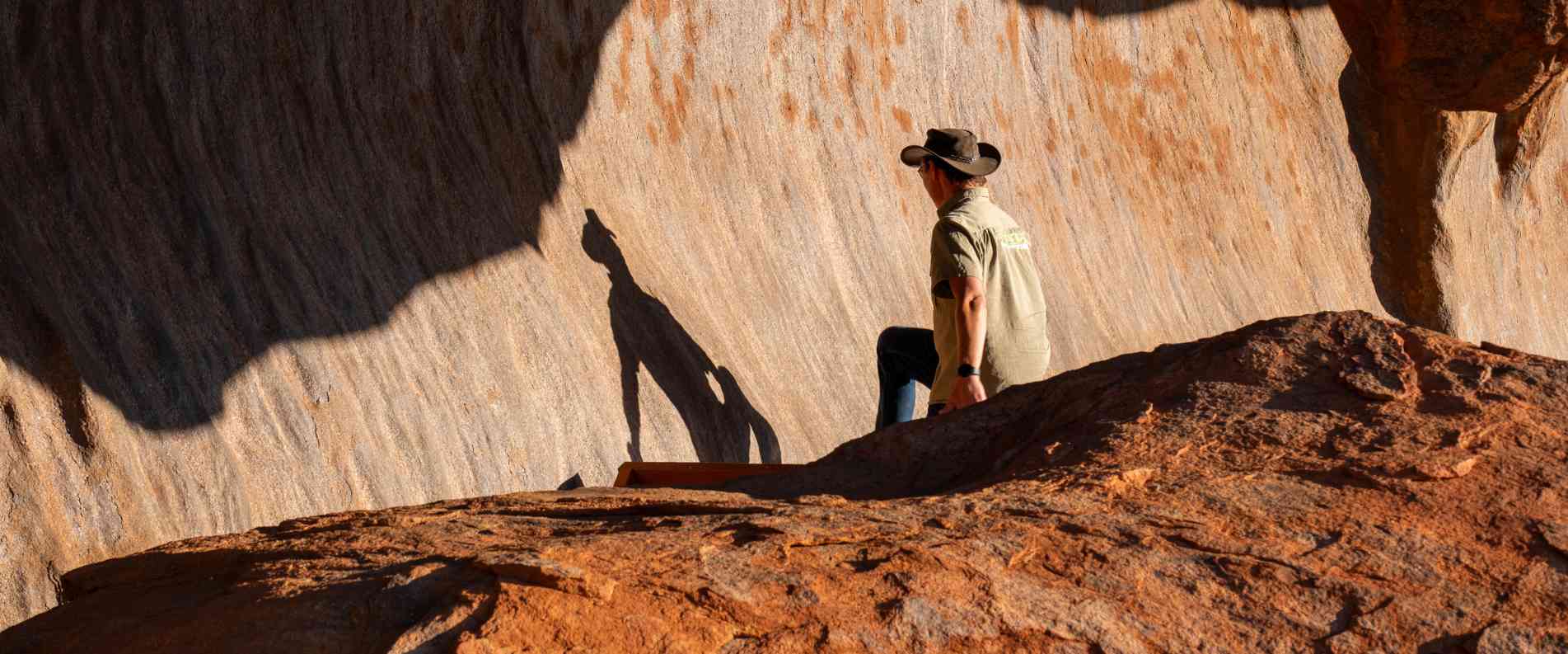 Man observing his shadow on a rock