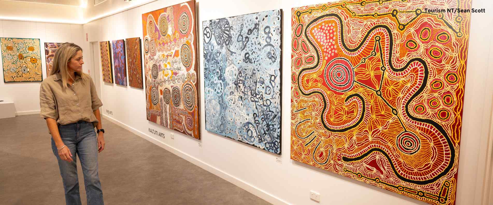 Woman looking at colourful Aboriginal paintings